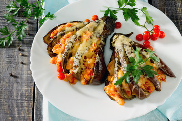 Baked eggplant with cheese, tomatoes and chicken on a dark woode