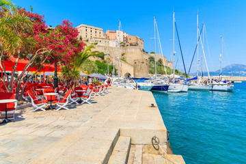 View of restaurant and citadel with houses in Calvi port, Corsica island, France
