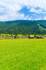 Green field in summer landscape of Alps Mountains, Weissensee lake, Austria