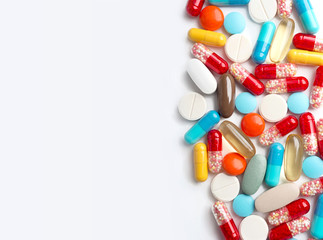 Spilled the variety of medicine capsules and pills on the white surface.