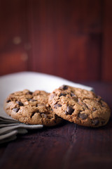 Cookies with chocolate crumbs on linen napkin on dark brown background
