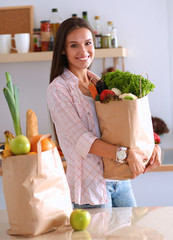 Young woman holding grocery shopping bag with vegetables 