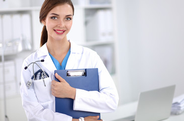 Smiling female doctor with a folder in uniform standing at