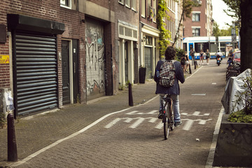 Senhor a andar de bicicleta numa pequena rua em Amsterdão