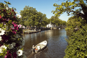 Barco a descer um canal em Amsterdão com flores em primeiro plano