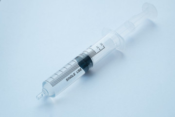 syringe with clear liquid on light background