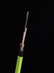 Green Nylon coated fiber optic cable with stripped and exposed fibers lit by green laser light in front of a black background, Melbourne 2015  - 90728037