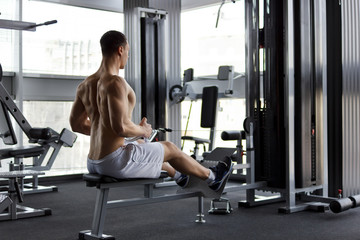 Fototapeta na wymiar Athletic strong bodybuilder execute exercise in sport gym hall