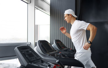 Fototapeta na wymiar Handsome gym man running on the treadmill