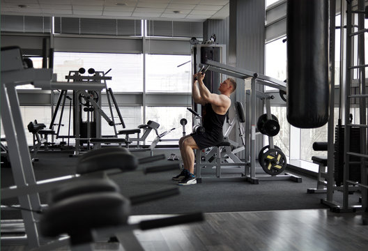 Athletic strong bodybuilder execute exercise in sport gym hall