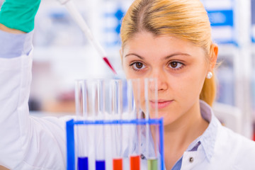 Young female scientist loads samples for DNA amplification by PC