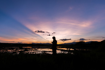 Silhouette of a man standing in a cornfield at sunset reflected