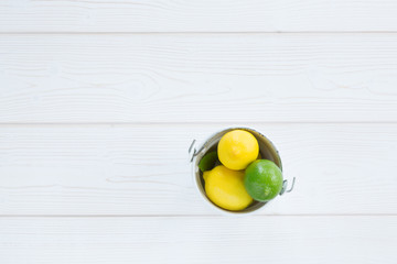 lemon yellow and lime green in a bucket on a white wooden background from above