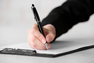 Female hand with pen writing on paper at workplace