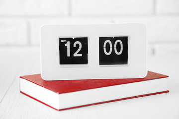 Modern Clock and book, on light wall background