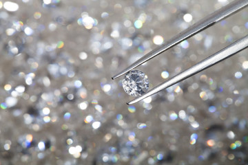 diamond held by tweezers close up. more diamonds out of focus in