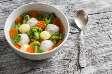 soup with chicken meat balls, potatoes, broccoli and carrots in a white bowl, a Healthy and tasty lunch