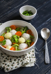soup with chicken meat balls, potatoes, broccoli and carrots in a white bowl, a Healthy and tasty lunch