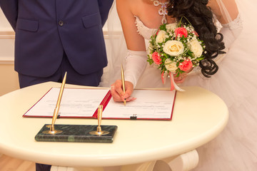 registration of marriage, the bride with a bouquet of flowers signed a marriage contract with a...