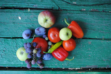 Vegetables and fruits on the green backround (tomatos, paper, apples, grapes, plums)