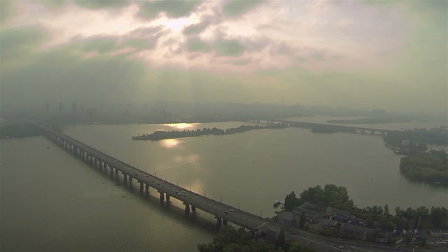 Gloomy  sky and sunlight over foggy river with bridge. Aerial panorama

