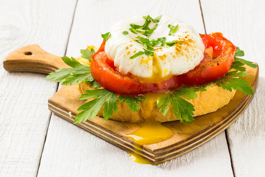 Poached egg on toast with tomatoes and parsley