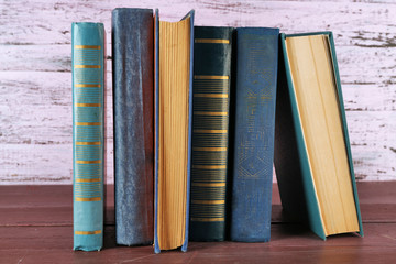 Stack of books on wooden table on pink wooden wall background