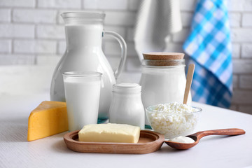 Dairy products on wooden table, on brick wall background