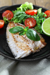 Dish of fish fillet with salad and lime on table close up