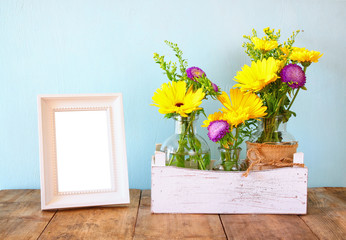 summer bouquet of flowers next to blank vintage photography frame 