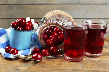 Glasses of sweet homemade cherry compote on table on wooden background