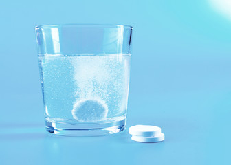 Glass of water and pills on blue background