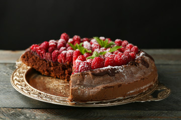 Cake with Chocolate Glaze and raspberries on tray on dark background