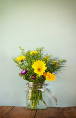 summer bouquet of flowers on the wooden table with mint background