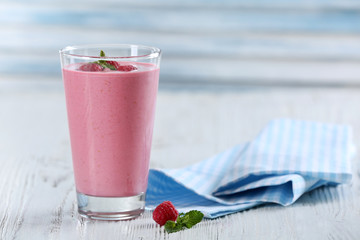 Glass of raspberry milk shake with berries on wooden background