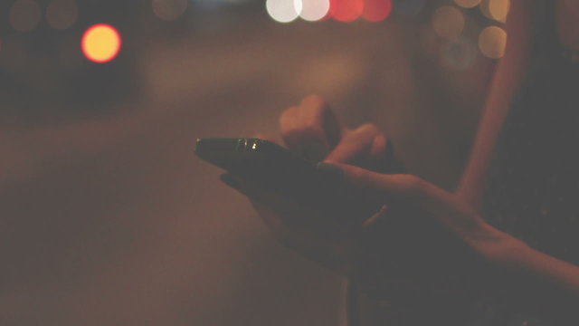 Using cellphone outdoors - with defocused city traffic.