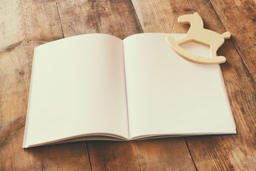 open blank notebook and wooden rocking horse toy over wooden table
