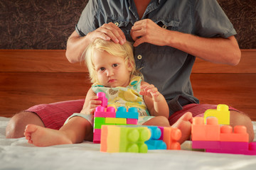 Naklejka premium little girl plays toy constructor father brushes her hair