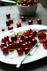 Sweet cherries on plate, on dark background