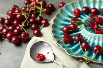 Sweet cherries on plate, on dark background