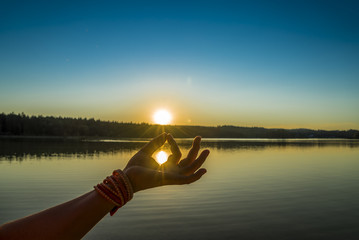 Junge Frau fängt Sonne mit Mudra-Geste beim Yoga - obrazy, fototapety, plakaty