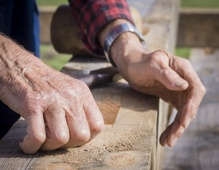 Old Man's Hands Resting on Wooden Timber Beam