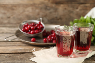 Two glasses with cherry juice on table, on wooden background