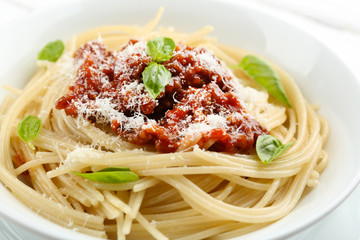Spaghetti Bolognese with parmesan cheese in white bowl, on color wooden background