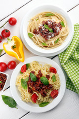Spaghetti Bolognese on white plate, on color wooden background