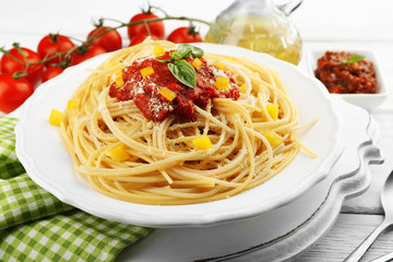 Spaghetti with tomato sauce and cheese on white plate, on color wooden background
