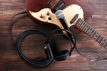 Naklejka premium Electric guitar with microphone and headphones on wooden table close up