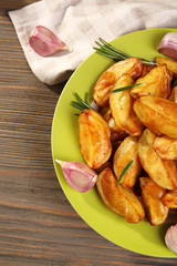 Baked potato wedges on wooden table, top view