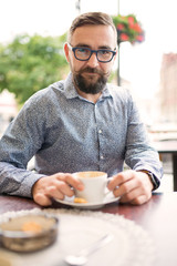 Elegant man drinking coffee outdoors