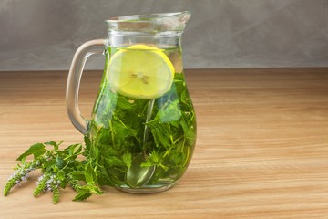 Fresh homemade mint tea. Tempting summer refreshment. Healthy, refreshing drink without sugar. Peppermint tea in a glass jar with lemon. Preparing tea.
